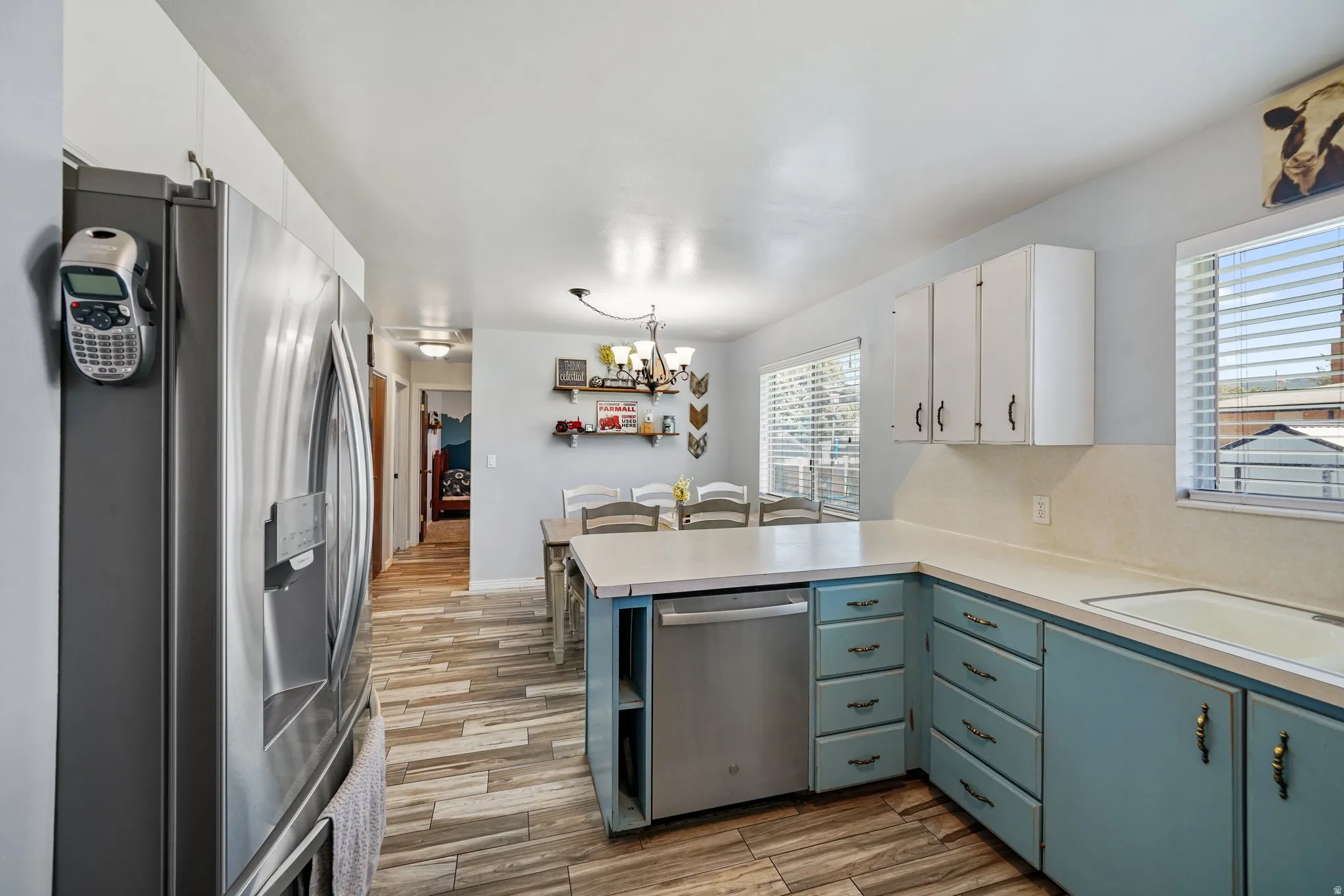 Kitchen with white cabinets, stainless steel appliances, light countertops, and light wood-style flooring