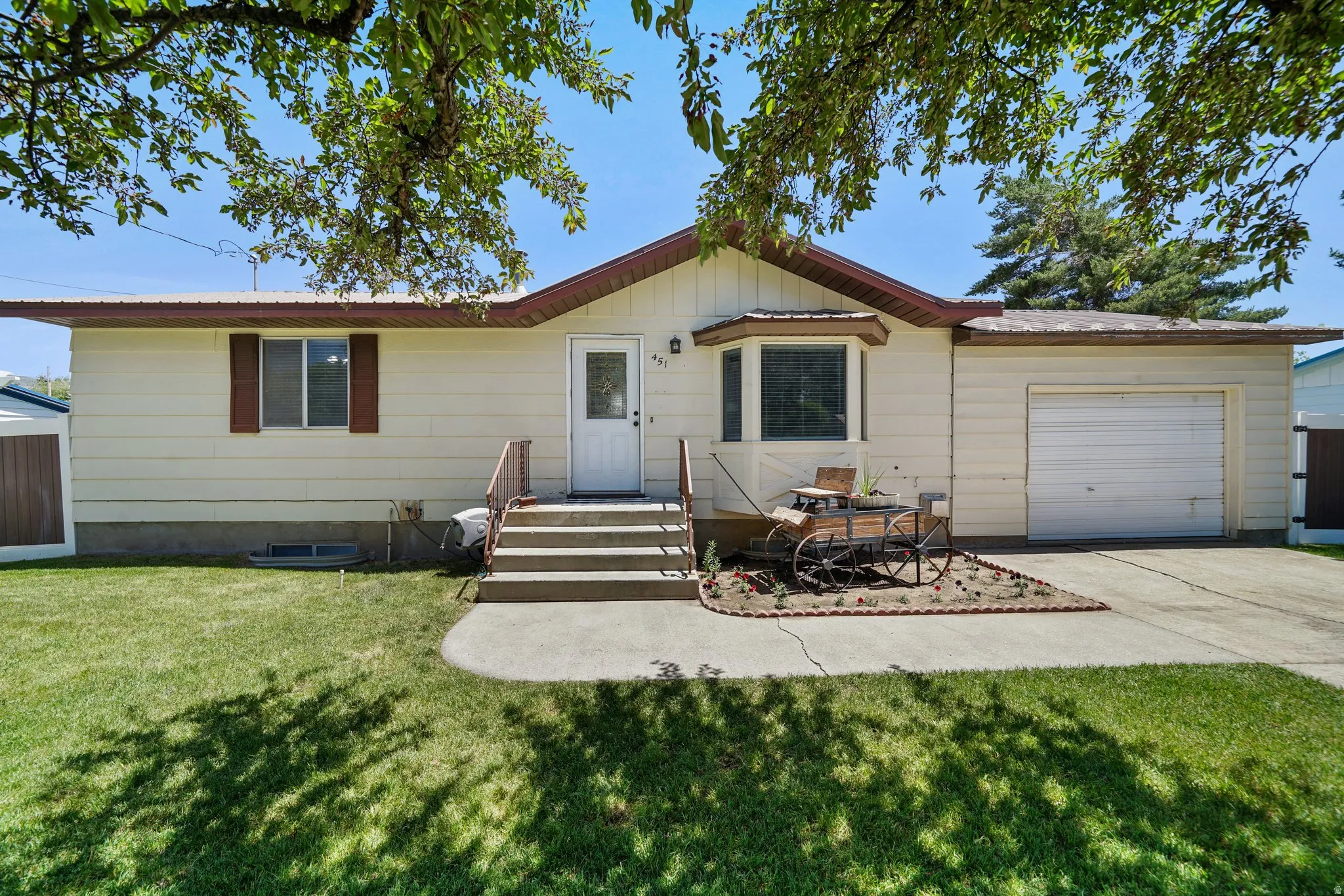 Ranch-style house with an attached garage, a front yard, concrete driveway, and a metal roof