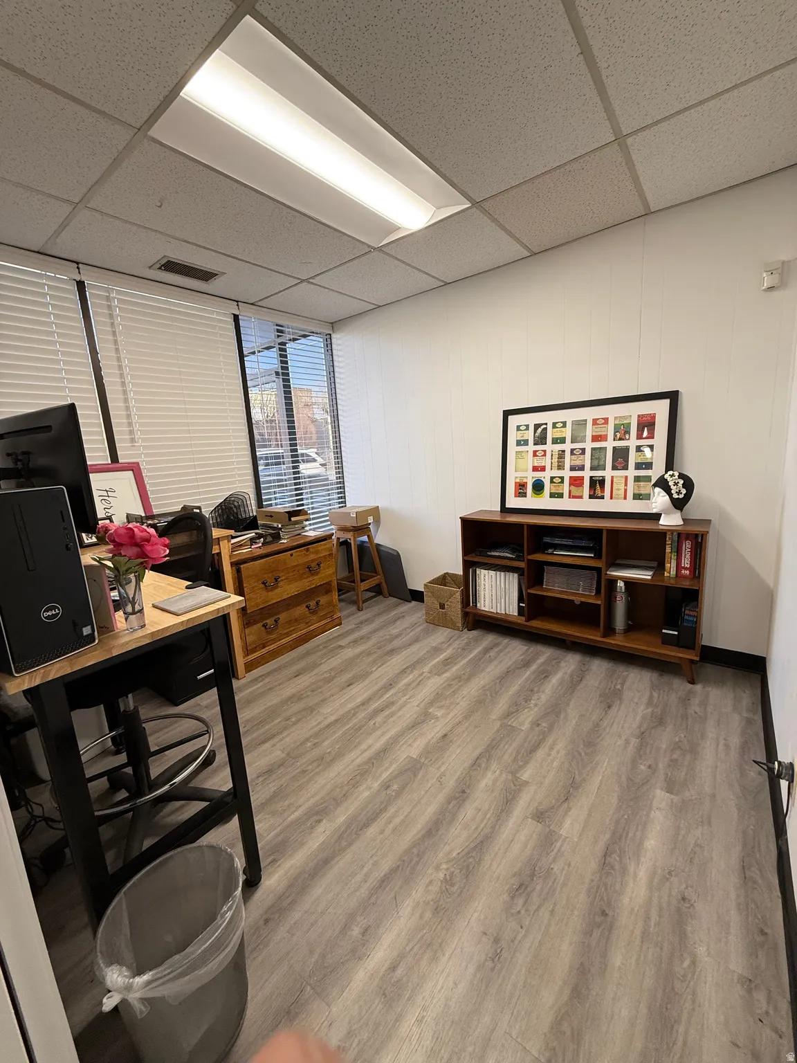 Office area featuring a paneled ceiling, light wood finished floors, and a decorative wall