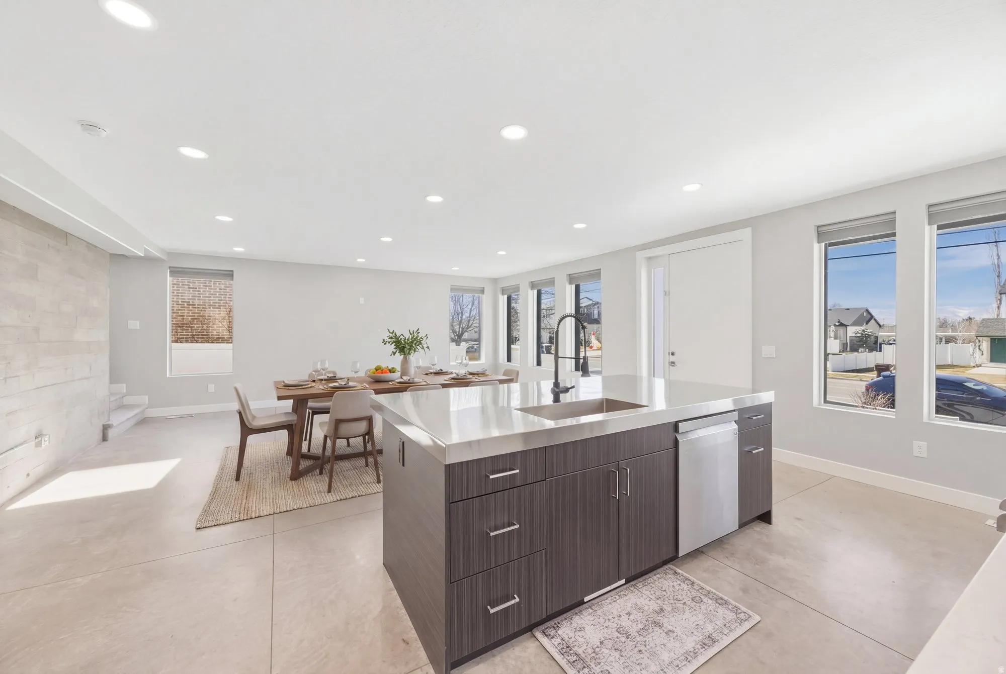 Kitchen featuring dark wood finish cabinetry, modern cabinets, an island with sink, stainless steel dishwasher, and recessed lighting
