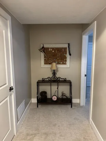 Hall with light colored carpet and baseboards