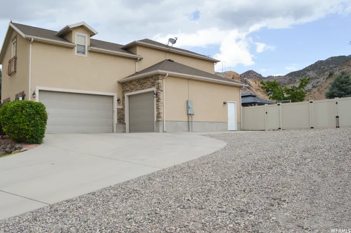 View of home's exterior with a gate, stucco siding, driveway, and a mountain view