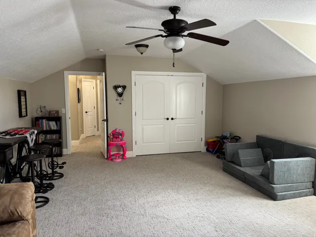 Game room with a textured ceiling, carpet flooring, lofted ceiling, and a ceiling fan