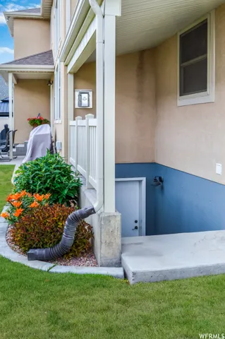 Property entrance featuring stucco siding, a shingled roof, and a yard