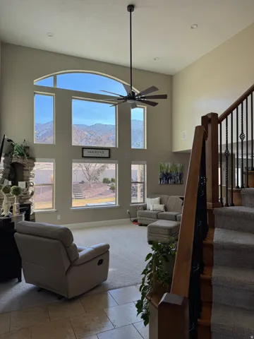 Living room featuring a towering ceiling, a fireplace, stairway, a ceiling fan, and recessed lighting