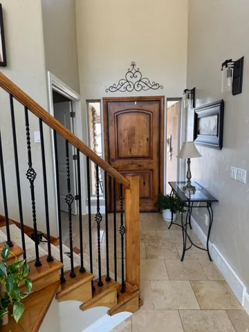 Entrance foyer with a textured wall, stairway, a towering ceiling, and light stone finish flooring