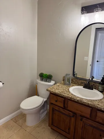 Half bath with vanity, a textured wall, and light tile patterned flooring