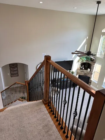 Staircase with a fireplace, a ceiling fan, and wood finished floors