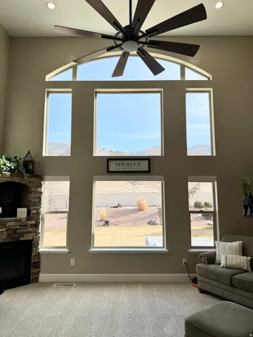 Living area featuring a high ceiling, recessed lighting, ceiling fan, a fireplace, and carpet