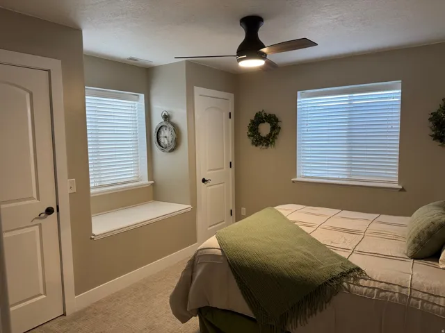 Bedroom featuring ceiling fan, light carpet, a textured ceiling, and multiple windows