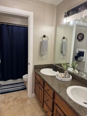 Full bathroom featuring double vanity and shower / bath combination with curtain