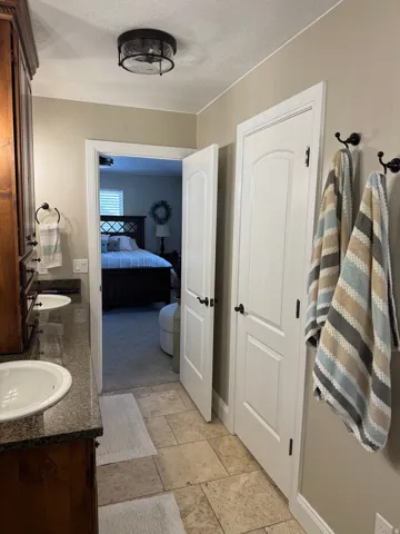 Bathroom featuring double vanity, a textured ceiling, and ensuite bathroom