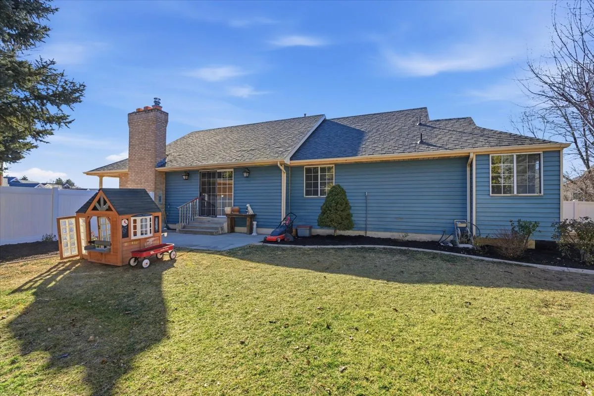 Back of property with a patio area, roof with shingles, and a chimney