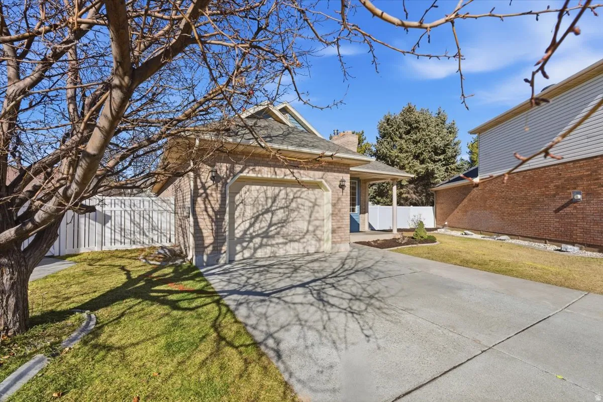 View of front of property with a chimney, concrete driveway, brick siding, and an attached garage