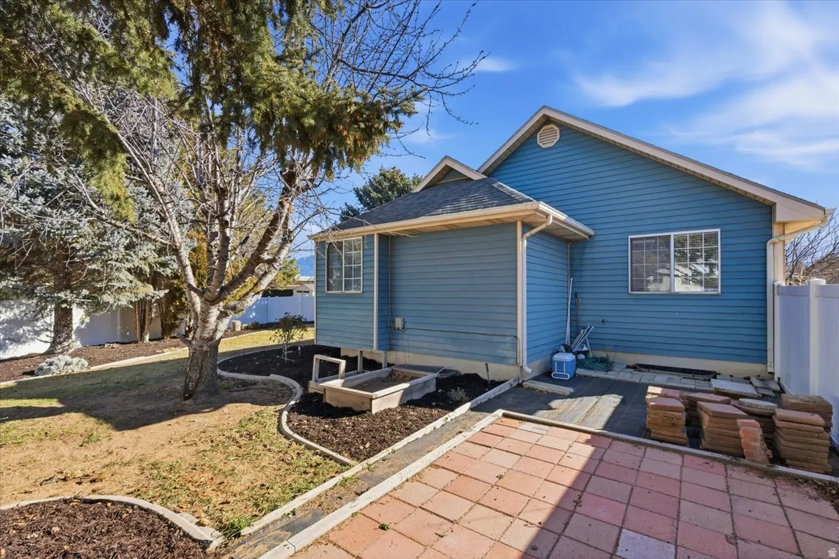 Rear view of property with a garden, a patio, and a shingled roof