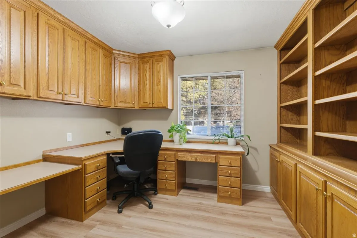 Home office featuring light wood-type flooring and built in desk