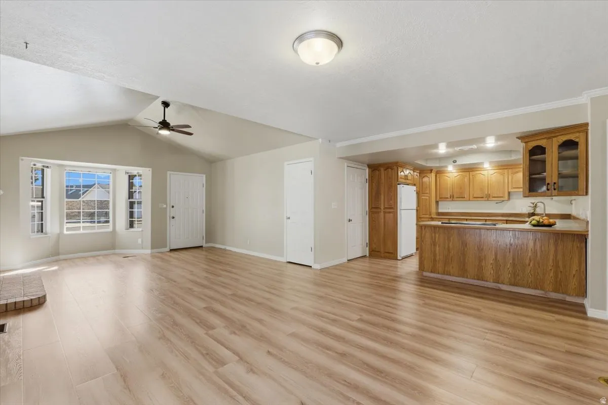 Unfurnished living room with light wood-style flooring, a ceiling fan, and lofted ceiling