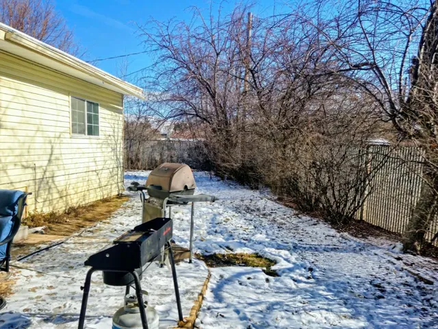 Snow covered patio featuring a fenced backyard and grilling area