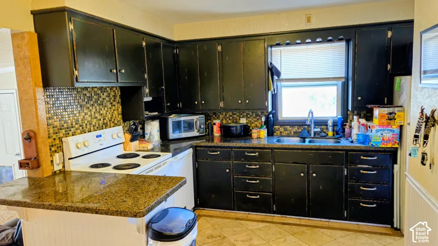 Kitchen featuring ample cabinetry, a mosaic tile backsplash, a double basin sink, and a window