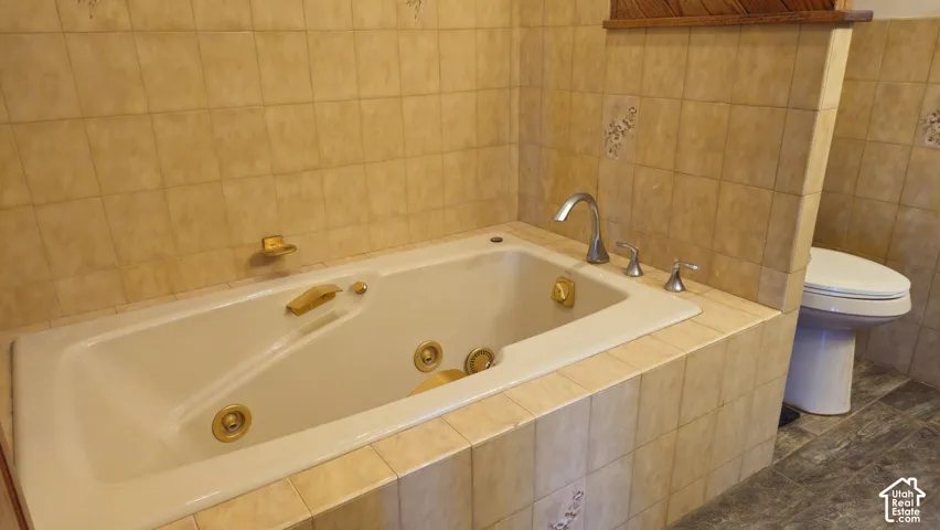 Jetted soaking tub with gold-tone fixtures and tile surround