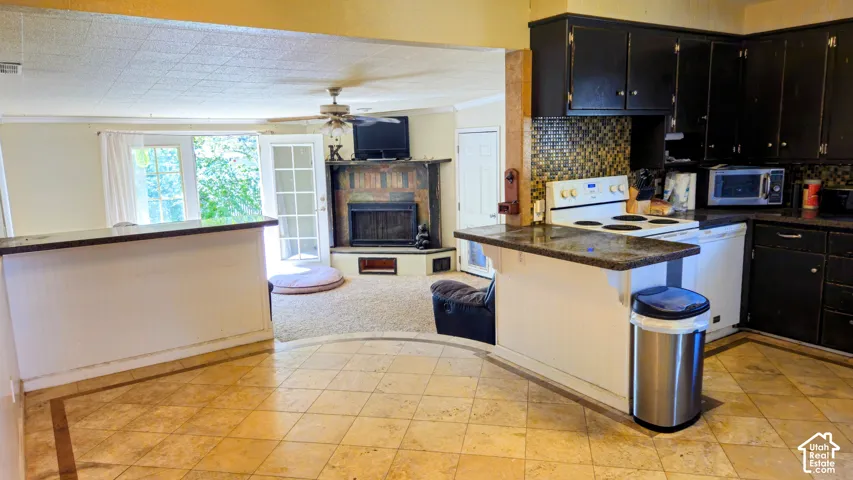 Kitchen featuring dark cabinetry, mosaic tile backsplash, and a breakfast bar with a stone-finish countertop