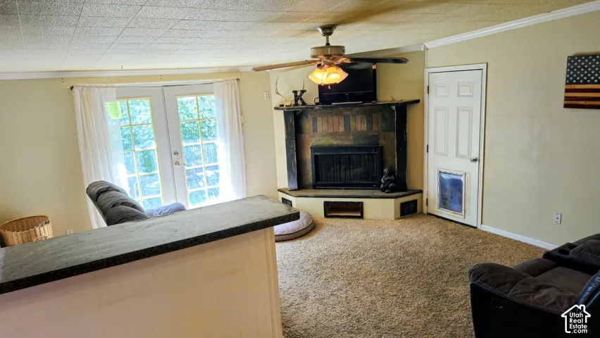Corner fireplace with a stone surround, ceiling fan, and double French doors with transom windows