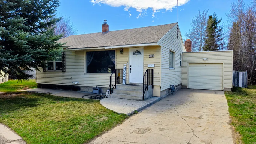 View of front facade with a chimney, driveway, a garage, and a front yard