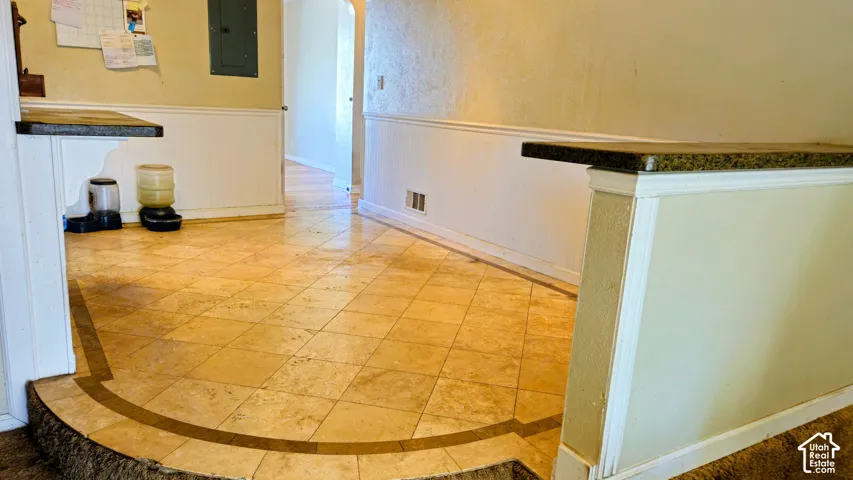 Tiled flooring with contrasting border, wainscoting, and a partial wall with a granite-style countertop
