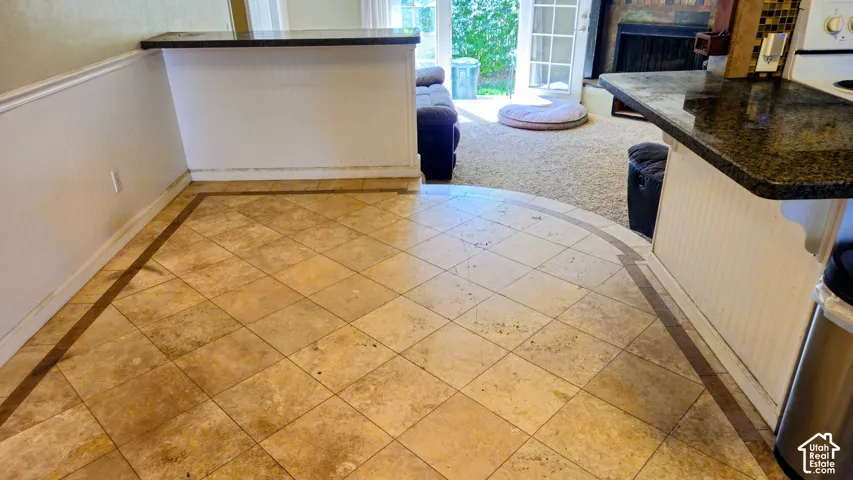 Tile flooring with decorative border, white paneling, and a dark stone countertop