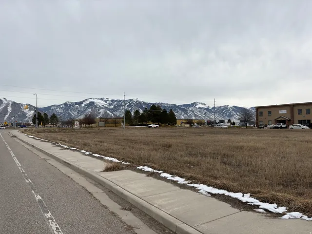 View of asphalt street featuring a mountain view, sidewalks, and curbs