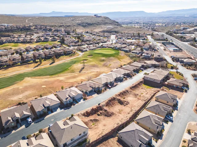 Aerial view of property and surrounding area with a local golf course, mountains, and nearby suburban area
