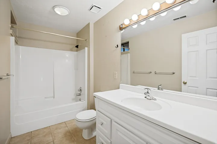 Bathroom featuring a white vanity with integrated sink, a large wall-mounted mirror, and a white shower/tub combination with a chrome shower rod