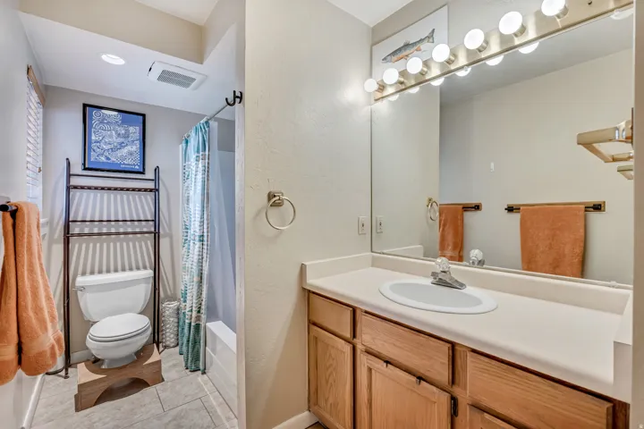 Bathroom with vanity, shower / bathtub combination with curtain, and light tile patterned floors