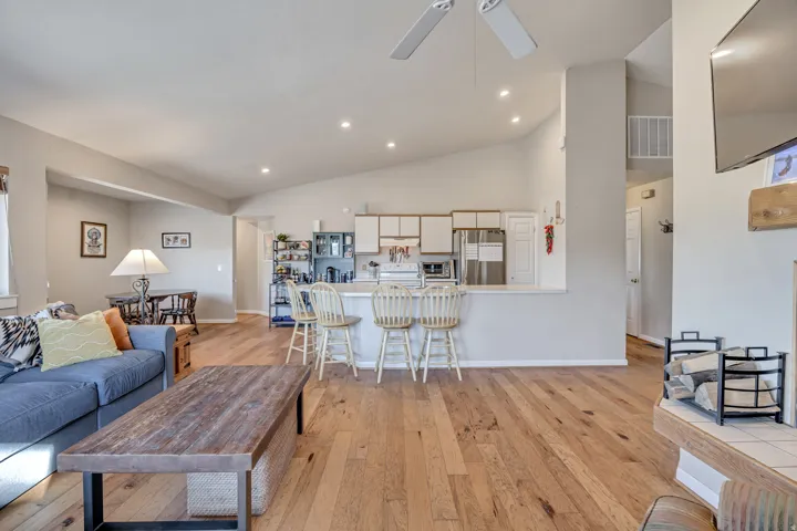 Living area featuring light wood-style flooring, high vaulted ceiling, and recessed lighting