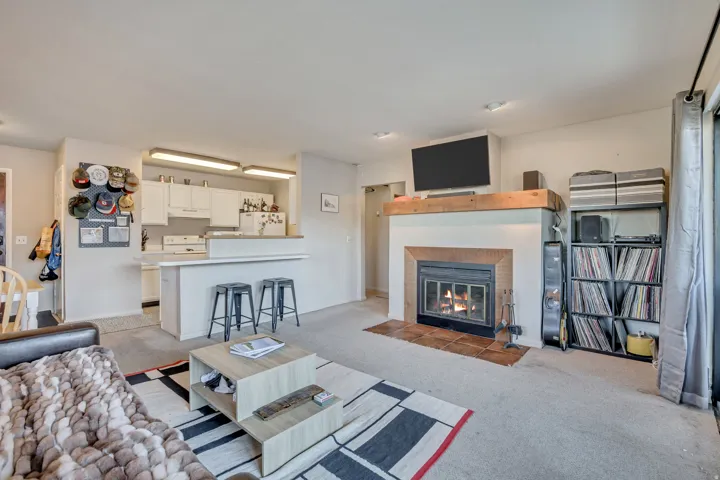 Living area with light carpet and a tile fireplace