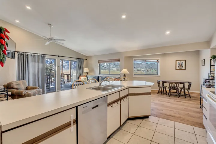 Kitchen featuring open floor plan, light countertops, stainless steel dishwasher, lofted ceiling, and recessed lighting
