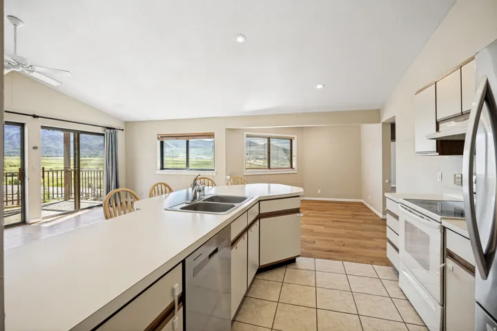 Kitchen featuring an integrated counter with a double-basin stainless steel sink, white cabinetry with wood-tone accents, and a stainless steel dishwasher