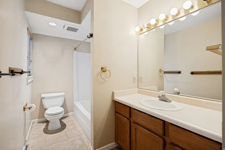 Bathroom featuring a vanity with wood-finish cabinetry, a single basin sink, and a large wall-mounted mirror