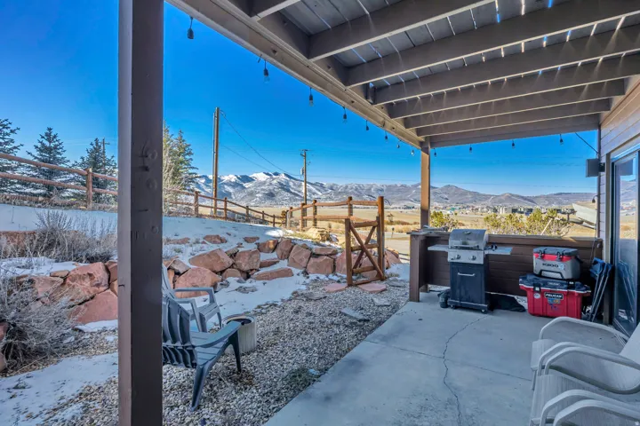 Snow covered patio with a patio, a mountain view, and grilling area