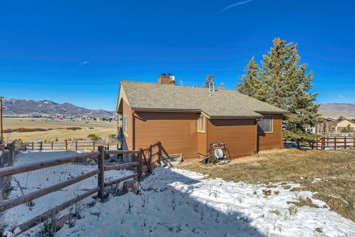View of side of property featuring a mountain view, a shingled roof, and a chimney