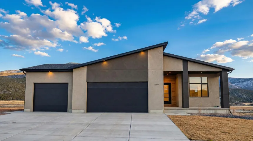 Contemporary house with a mountain view, an attached garage, stucco siding, concrete driveway, and a porch