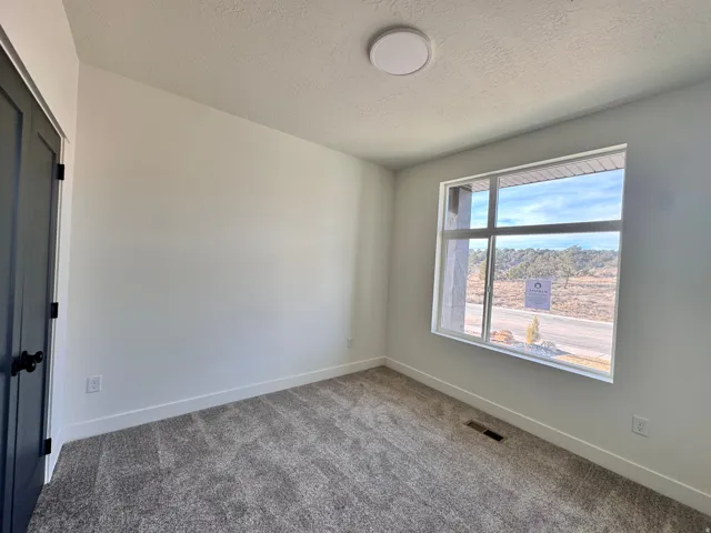 Carpeted empty room with baseboards and a textured ceiling