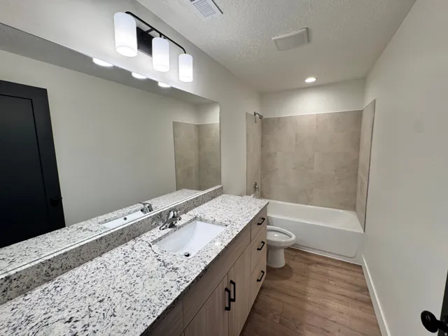 Full bathroom featuring shower / bathtub combination, vanity, dark wood-type flooring, and a textured ceiling