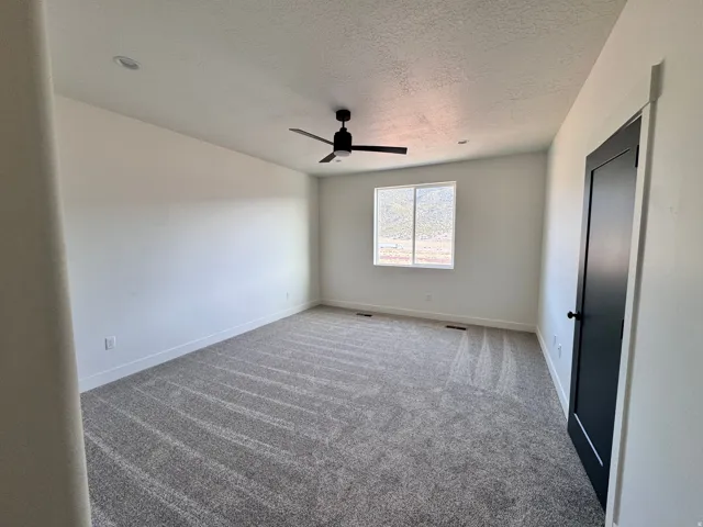 Spare room featuring carpet floors, a textured ceiling, and ceiling fan