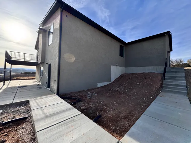 View of home's exterior featuring stairway, stucco siding, and a deck