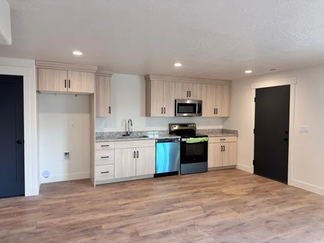 Kitchen featuring stainless steel appliances, light brown cabinetry, light wood finished floors, recessed lighting, and light stone countertops
