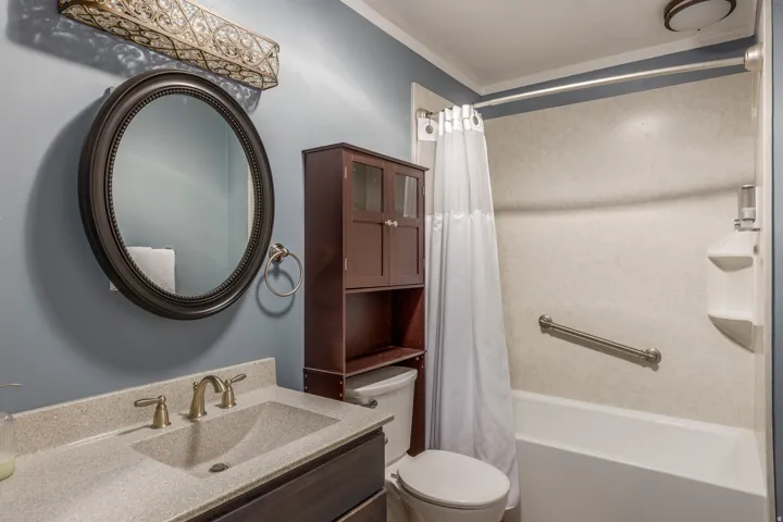 Bathroom featuring vanity, shower / tub combo with curtain, and crown molding