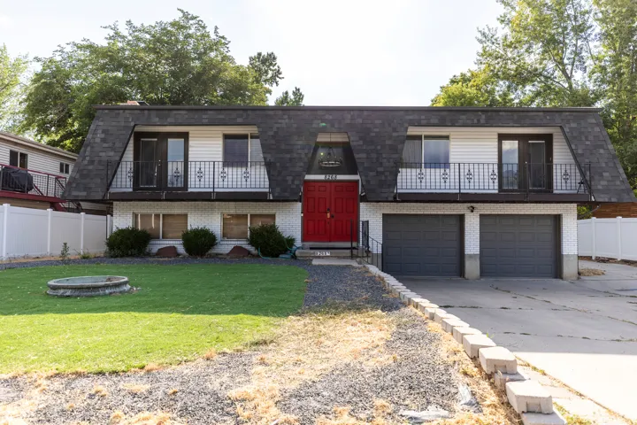 View of front of home featuring a balcony, brick siding, driveway, and a garage