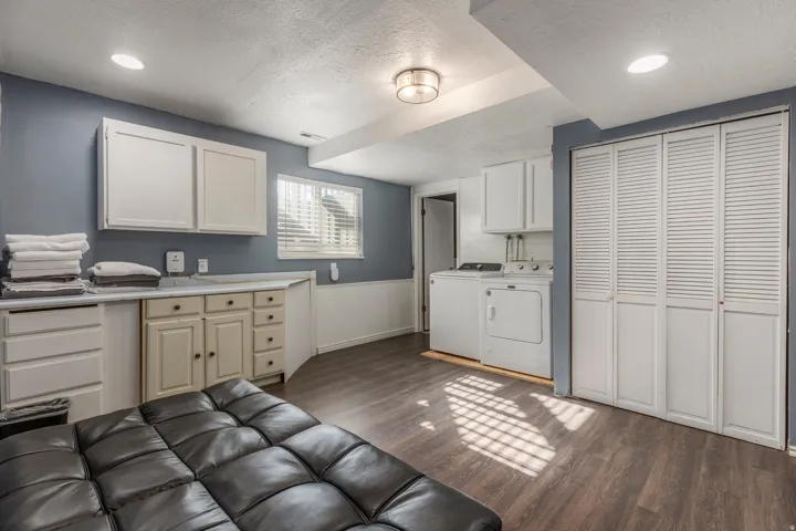 Washroom with wainscoting, dark wood-style floors, a textured ceiling, washing machine and dryer, and recessed lighting