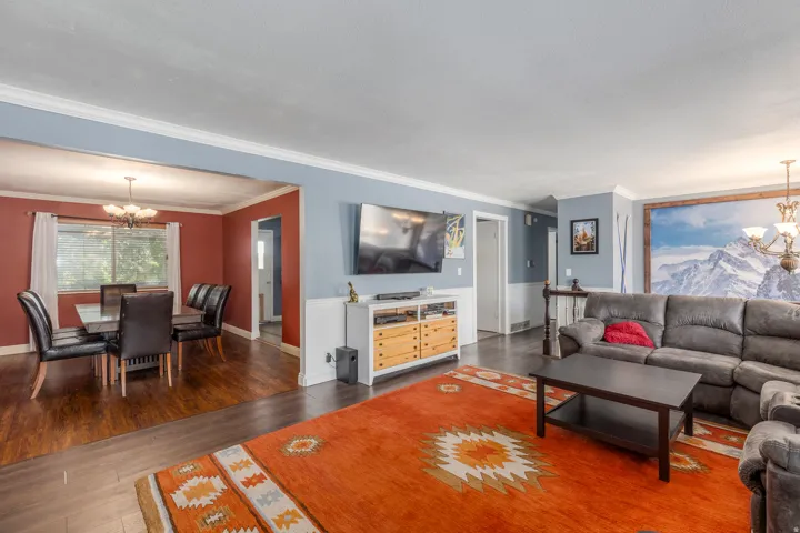 Living area with a chandelier, wood finished floors, and crown molding